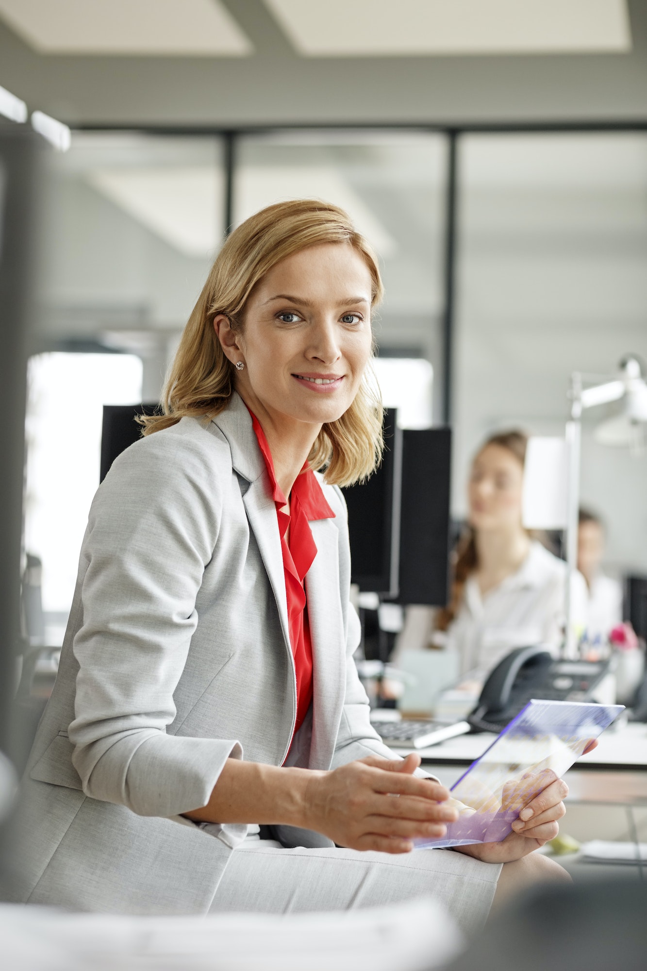 Portait of smiling businesswoman at desk in office holding futuristic tablet
